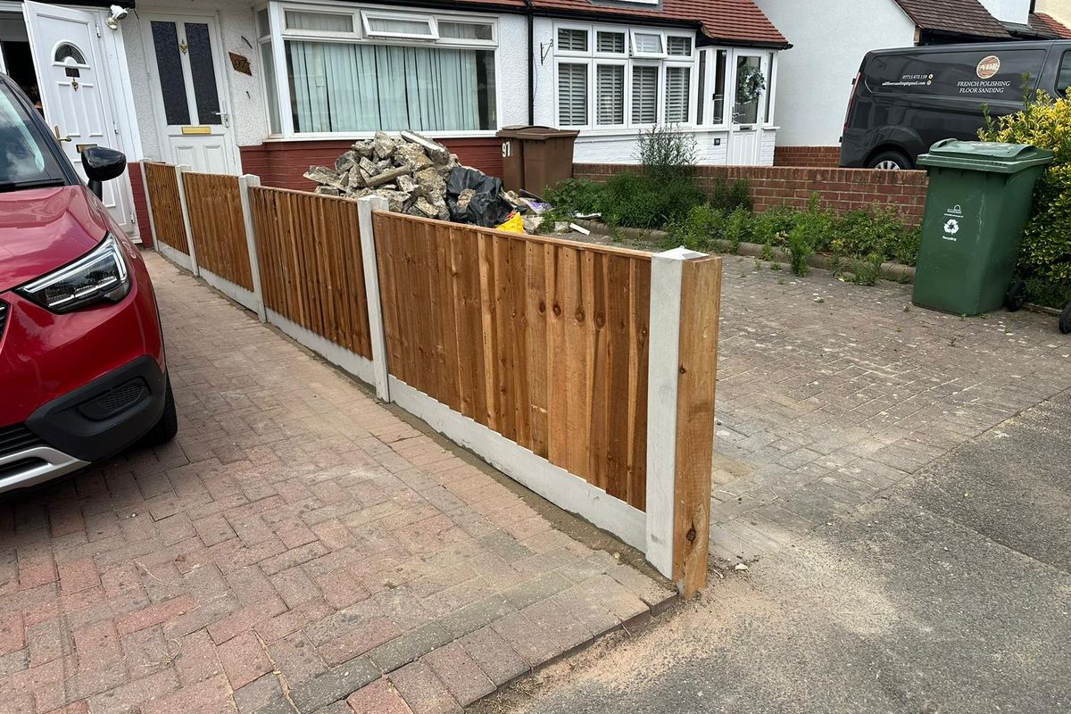 The same front garden after work: new closeboard fencing on concrete posts along the driveway boundary