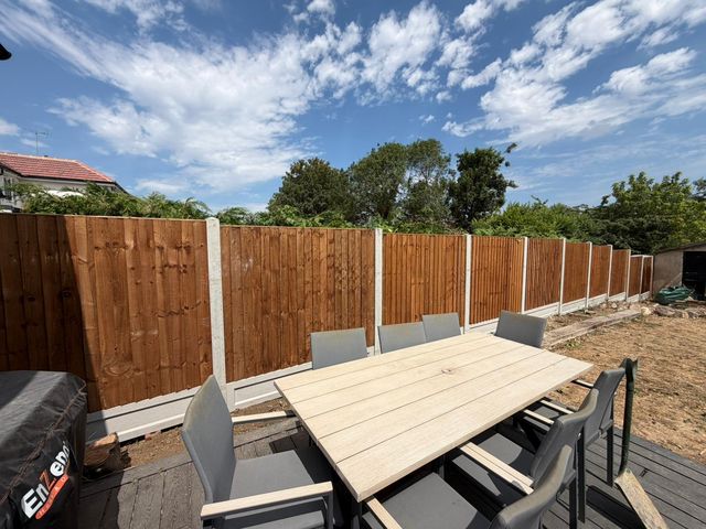 New closeboard panels on concrete posts behind a patio dining set on a sunny day