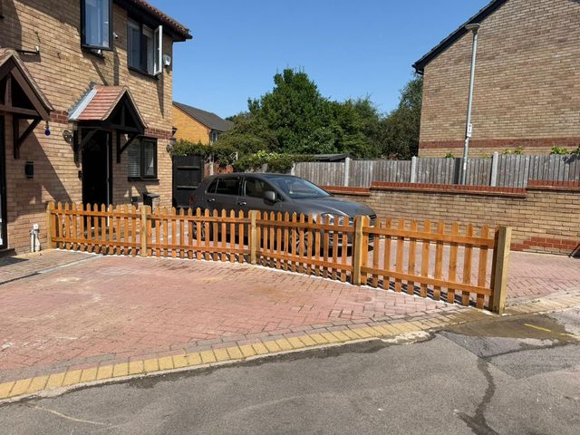 New rounded-top picket fencing along the edge of a block-paved front driveway