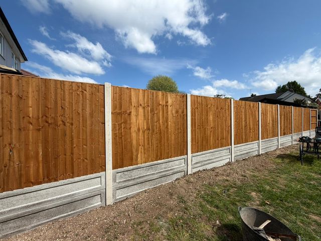 A long run of closeboard panels on concrete posts and gravel boards under a blue sky