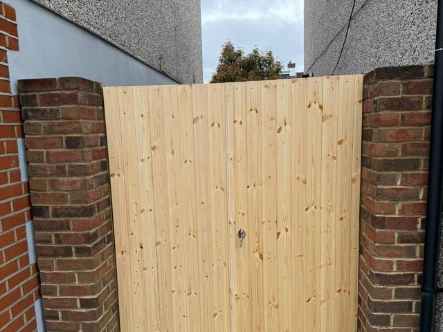 A pair of new pine gates hung between brick piers across a side passage