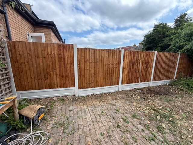 New closeboard panels on concrete posts running across the back of a paved garden