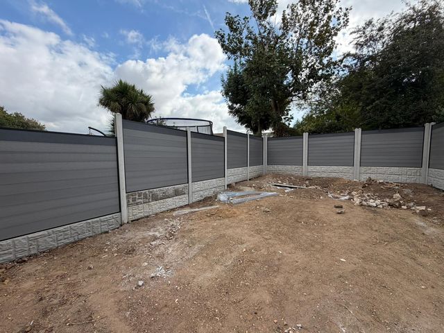 Grey composite fence panels on concrete posts around a cleared garden