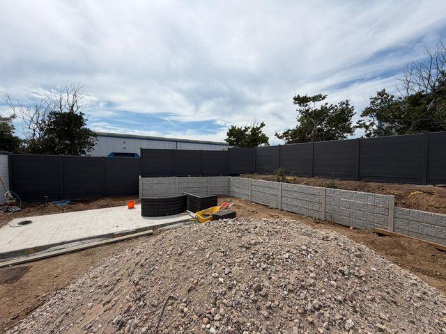 Grey composite fencing and concrete panel walls around a garden under construction